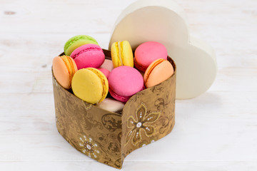 macaroon in a heart shaped box, a gift on a white wooden backgro
