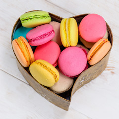 macaroon in a heart shaped box, a gift on a white wooden backgro