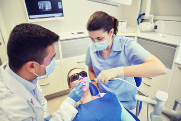 dentists treating male patient teeth at clinic