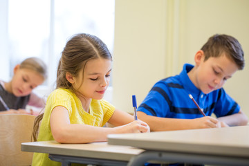 group of school kids writing test in classroom