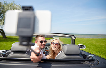 happy couple in car taking selfie with smartphone