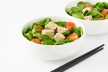 Vegan tofu salad with tomatoes and lamb's lettuce isolated on white background
