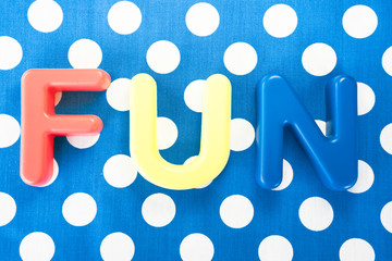 Fun made of plastic letters, blue dotted background