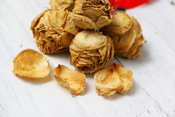 Dry rose with red ribbon on wooden background