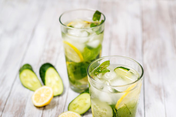 Water with lemon, mint and cucumber on wooden light background. Water Detox.