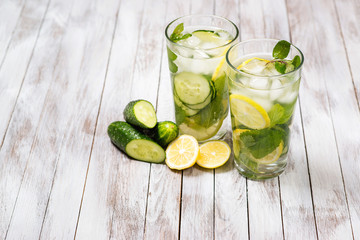 Water with lemon, mint and cucumber on wooden light background. Water Detox.