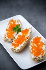 Red caviar on bread on white plate.