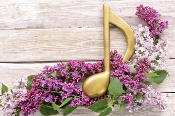 Golden note with blossom lilac on wooden background 