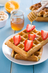 Waffles with strawberries and honey on blue wood

