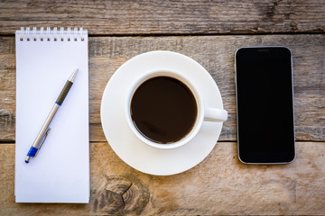 cup of coffee and smartphone with paper note on wood table backg