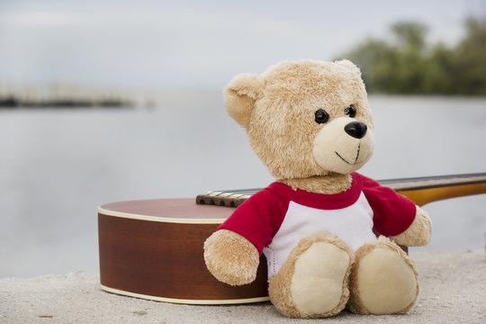 Ukulele and teddy bears on  river side in the evening.