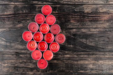 Many extinguished small red candles makig a diamond shape on wooden table top view with copy space