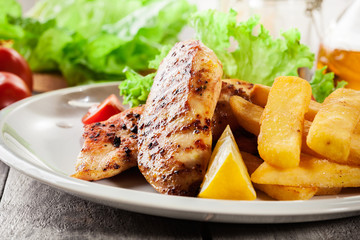 Grilled chicken breasts served with fries and fresh salad