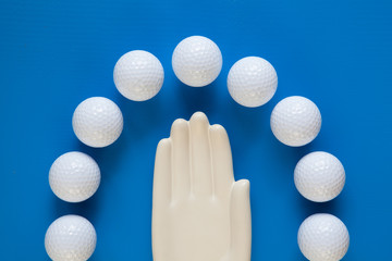 Detail of ceramic hand with golf balls on the blue wooden table