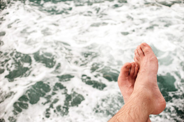 No person Unrecognizable man's legs, sitting on the edge of pontoon, outdoors against sea, texture