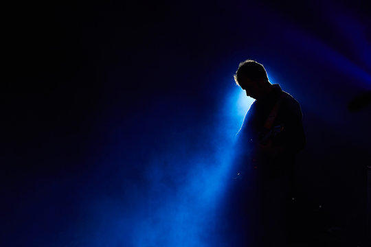 Chitarrista con faro blu su fondo nero