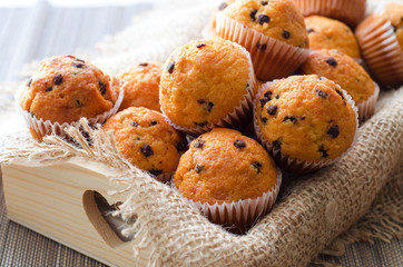 Little chocolate muffins in paper cupcake holder on the wooden tray with sacking napkin