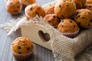 Little chocolate muffins in paper cupcake holder on the wooden tray with sacking napkin