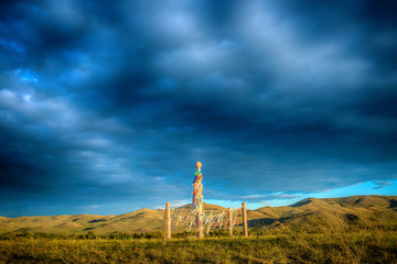 Antique stone totem in sunlight in summer field
