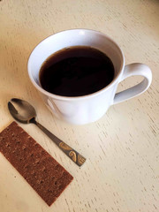 White cup of black coffee on wooden table