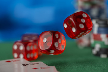 Red dice rotates in the air, casino chips, cards on green felt