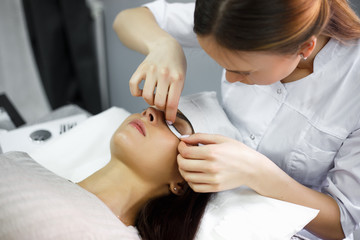 Fototapeta na wymiar eyelash extension procedure - master and a client in a beauty salon