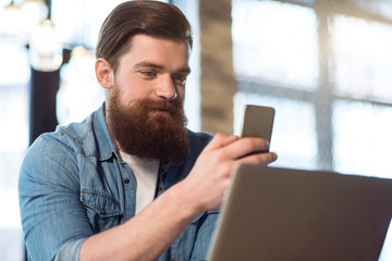 Delighted  bearded man sitting at the table   
