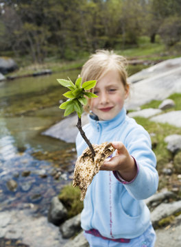 Girl att the beach with a sprout in her hand.