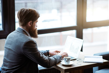 Pleasant bearded man sitting at the table       