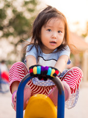 happy Asian child on a seesaw in sunset light.