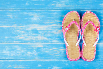View of flip-flops lying on blue wooden background.