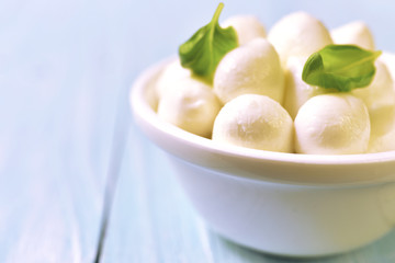 Small white mozzarella balls in a white bowl.