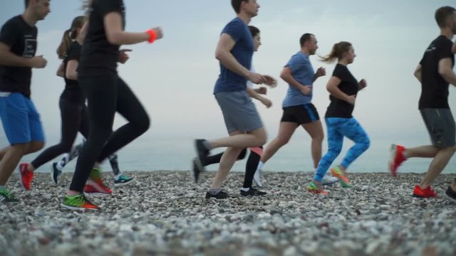group of sportsmen jogging along the sea slow motion