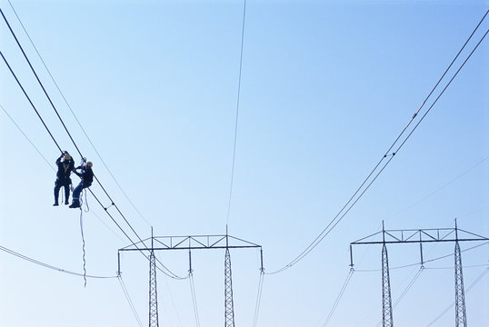 Men working on power lines, low angle view