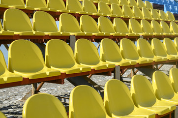 Fototapeta na wymiar Rows of yellow plastic seats in the stadium