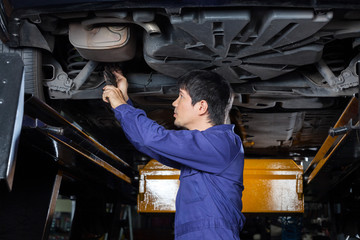 Fototapeta na wymiar Mechanic Examining Underneath Lifted Car
