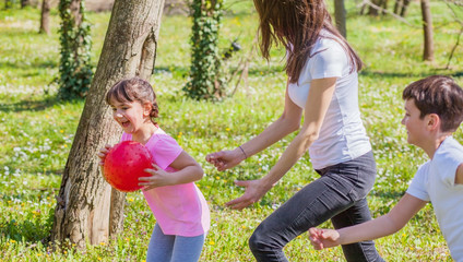 Family in the park playing with the ball. Mother and children having fun in the park