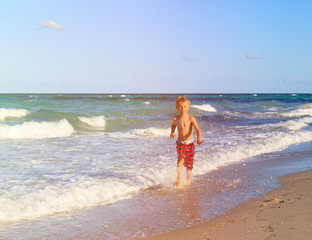 happy little boy running on sand beach