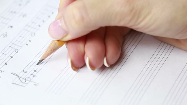 Hand with pencil and music sheet. composer writes music
