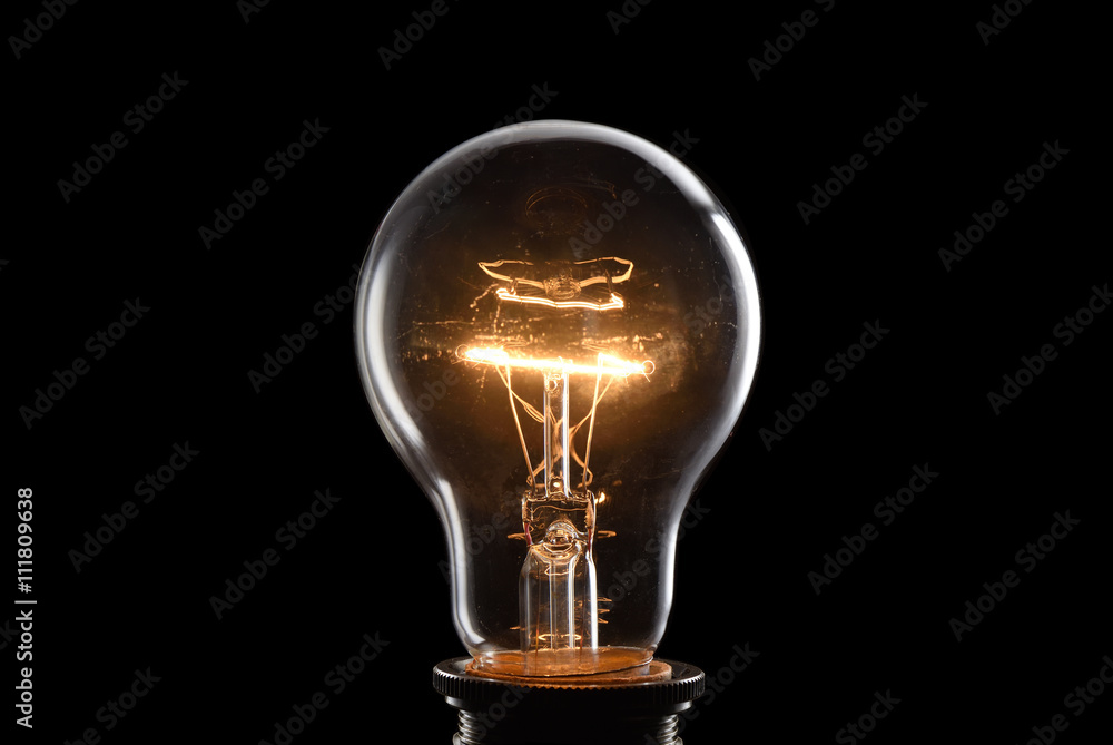 Wall mural close up glowing vintage light bulb. isolated on black backgroun