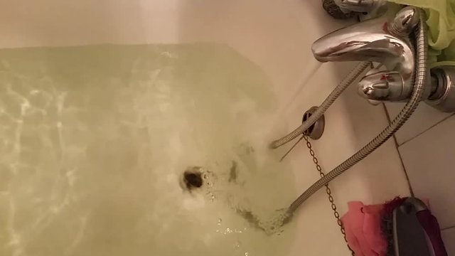 In bathroom water flows from the tap in silver