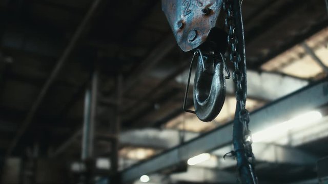 Close up shot of a swinging metal hook on abandoned factory. Scary, catastrophe, horror concept. Blackmagic URSA Mini RAW graded footage