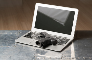 Black pistol on the keyboard of laptop
