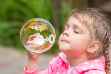 Five-year girl inflates a large circular bubble