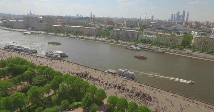 Aerial view over Gorky Park in Moscow on spring sunny day. Moscow river, many green trees, boats crossing the river, crowds of people, sky with fluffy clouds.    