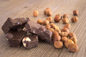 Pezzi di cioccolata fondente con nocciole su tavolo rustico. Primo piano