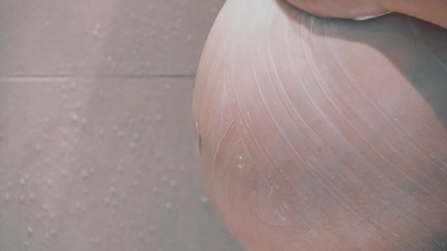 Schwangere Frau seift den Bauch in der Dusche. Und wascht ab.