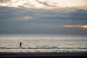 Fototapeta na wymiar Fishing. Evening shoot of solitary fisherman on an Australian beach.