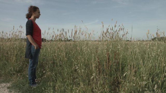 Donna con capelli ricci in un campo pensa e ricorda