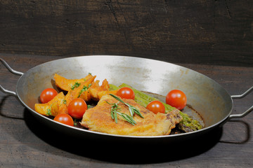 Cutlet with potato wedges, tomatoes, green asparagus, garnished